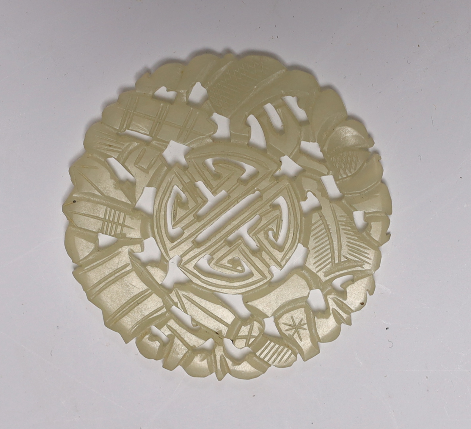 A Chinese carved pale celadon disc, 5.5cm in diameter